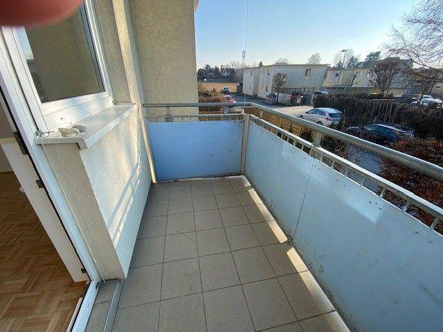 Balkon mit Fliesenboden und blauen Sichtschutzwänden, sonniger Ausblick.