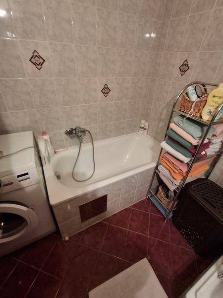 Badezimmer mit Badewanne, Waschmaschine und Fliesen in warmen Erdtönen.