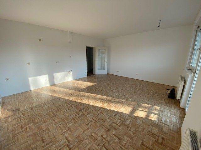 Geräumiges Wohnzimmer mit Parkettboden und viel natürlichem Lichteinfall.