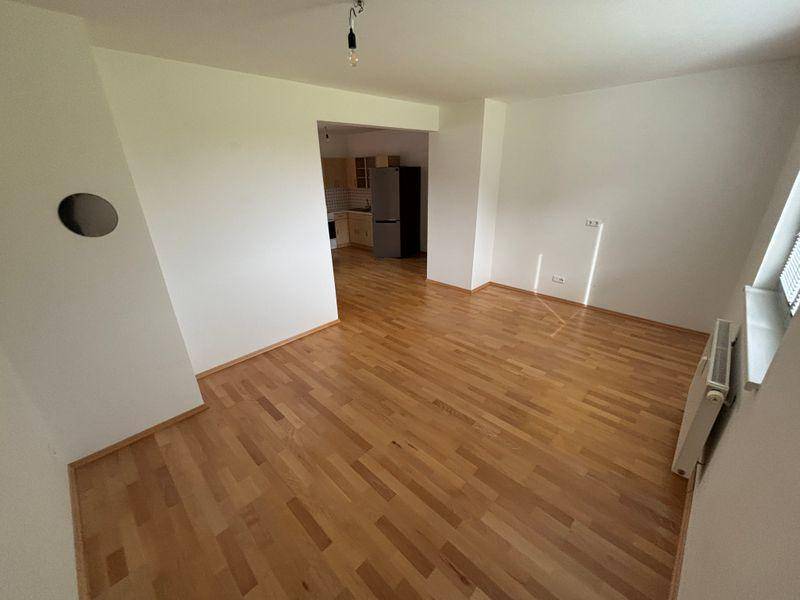 Geräumiger Wohnbereich mit Holzfußboden und offenem Übergang zur Küche.