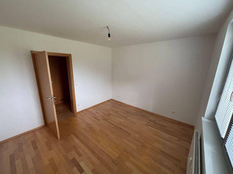 Leeres Schlafzimmer mit Holzfußboden und Fenster, ideal für individuelle Gestaltung.