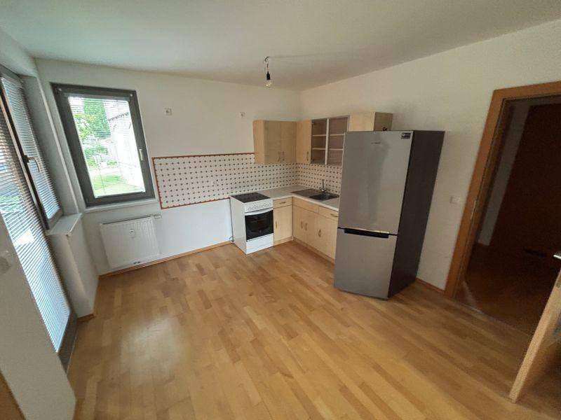 Einfache Küche mit Holzschränken, Kühlschrank und Herd, bereit zur Nutzung.