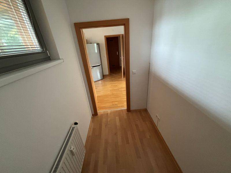 Heller Flur mit Holzfußboden und Zugang zu weiteren Räumen.