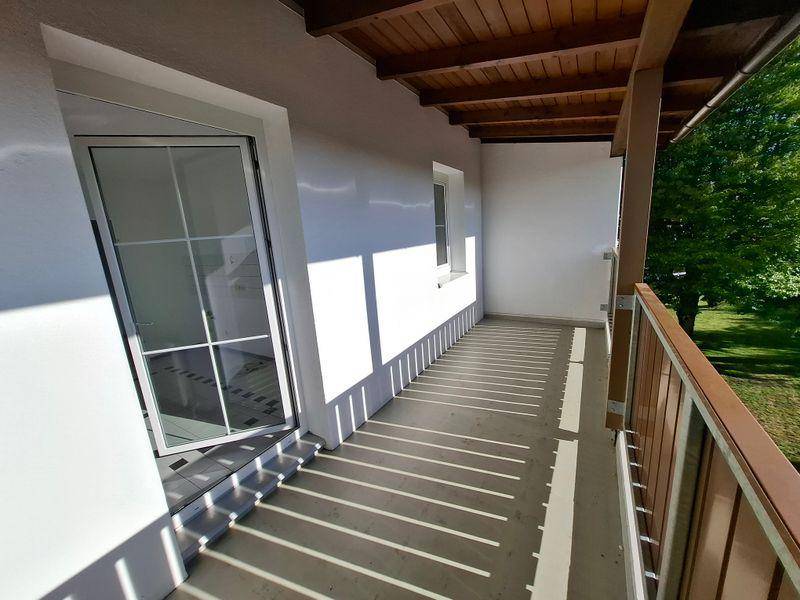 Geräumiger Balkon mit Holzdach und Blick ins Grüne, ideal für entspannte Stunden im Freien.