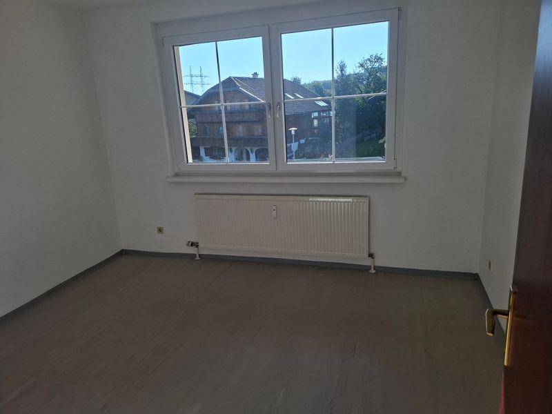 Geräumiges Zimmer mit Laminatboden und großem Fenster, das einen Blick auf ein traditionelles Haus bietet.