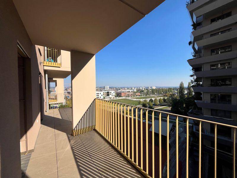Sonniger Balkon mit weitem Blick über die Stadt und grüne Parkanlagen.