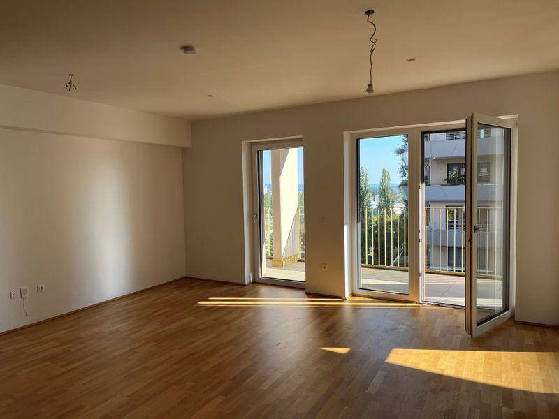 Lichtdurchflutetes Wohnzimmer mit Parkettboden und Zugang zu einem sonnigen Balkon.
