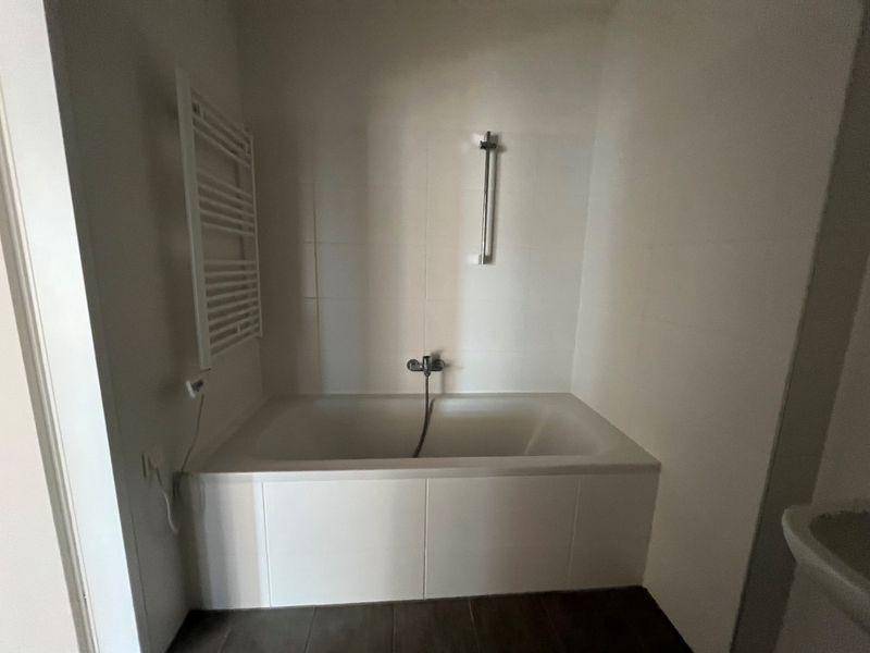 Modernes Badezimmer mit eingebauter Badewanne, Handtuchheizkörper und weißen Wandfliesen.