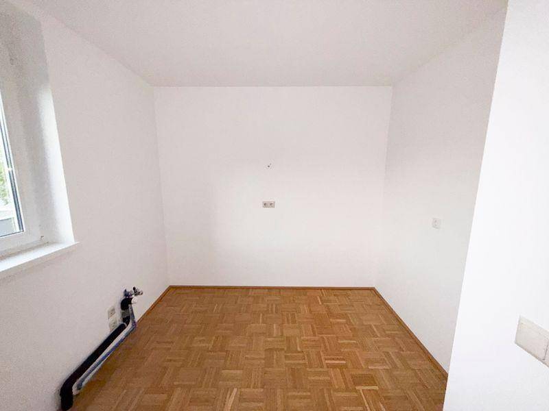 Leeres Schlafzimmer mit Parkettboden und einem Fenster, bereit zur Einrichtung.
