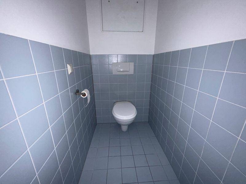 Kleines WC mit hellblauen Fliesen an den Wänden und auf dem Boden.