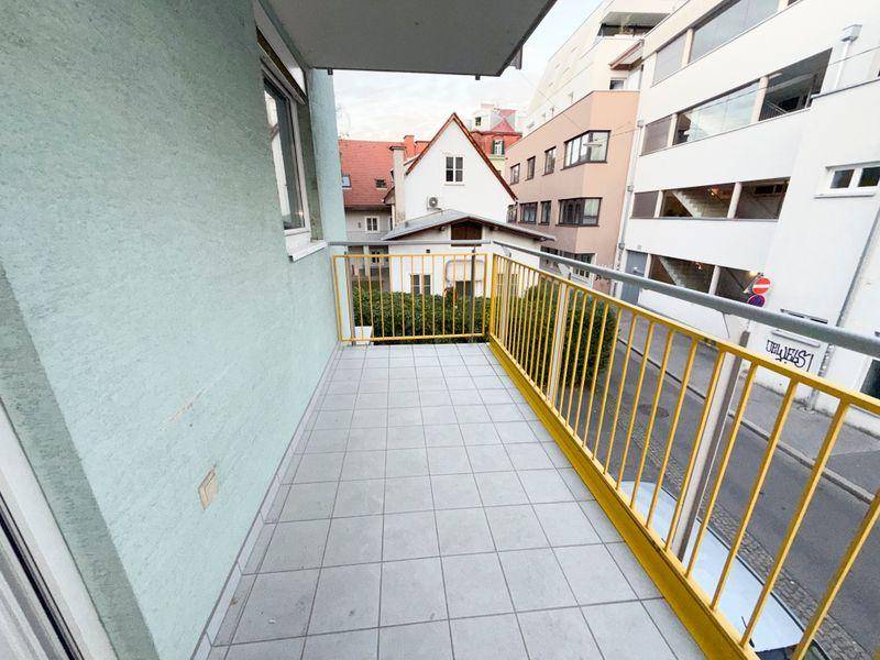 Balkon mit Fliesenboden und gelbem Geländer, bietet einen Blick auf die Umgebung.