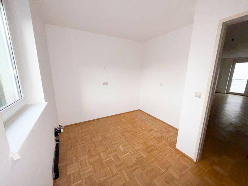 Leerer Raum mit Parkettboden und einem Fenster, bereit zur individuellen Gestaltung.