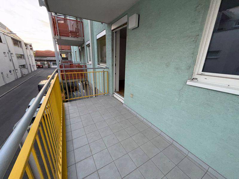 Geräumiger Balkon mit Fliesenboden und gelbem Geländer, zugänglich von einem Innenraum.