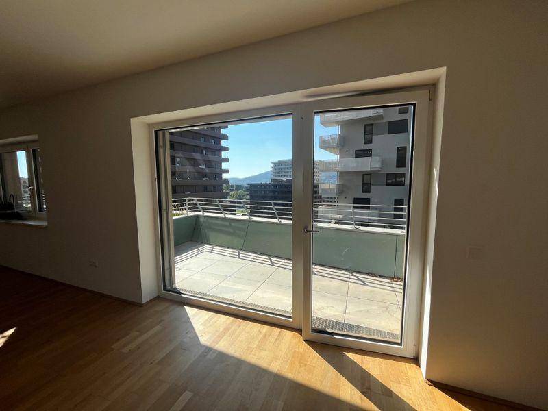 Heller Wohnraum mit Holzboden und großen Schiebetüren zum Balkon.