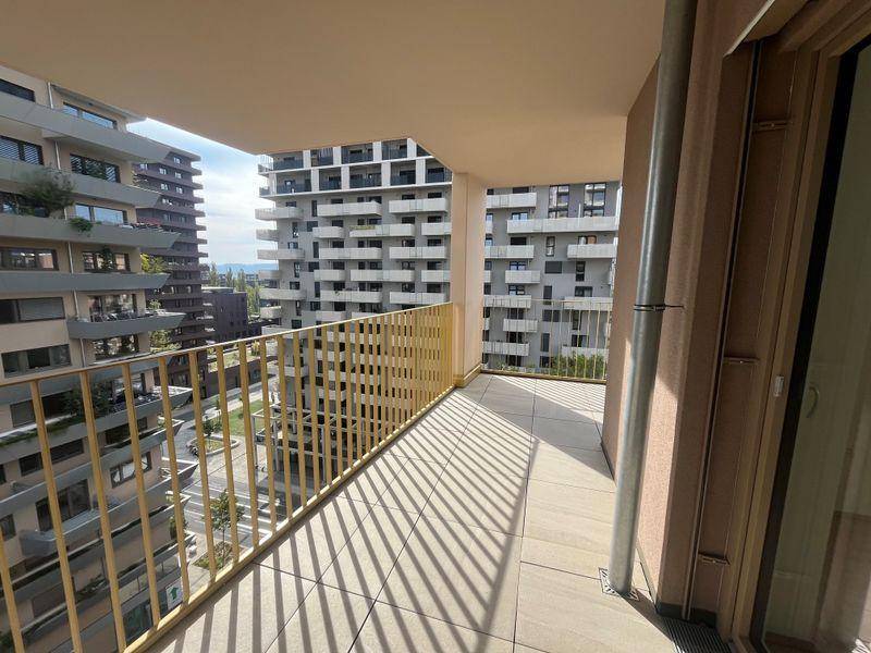 Geräumiger Balkon mit Fliesenboden und gelbem Geländer, bietet einen Blick auf die umliegenden Gebäude.