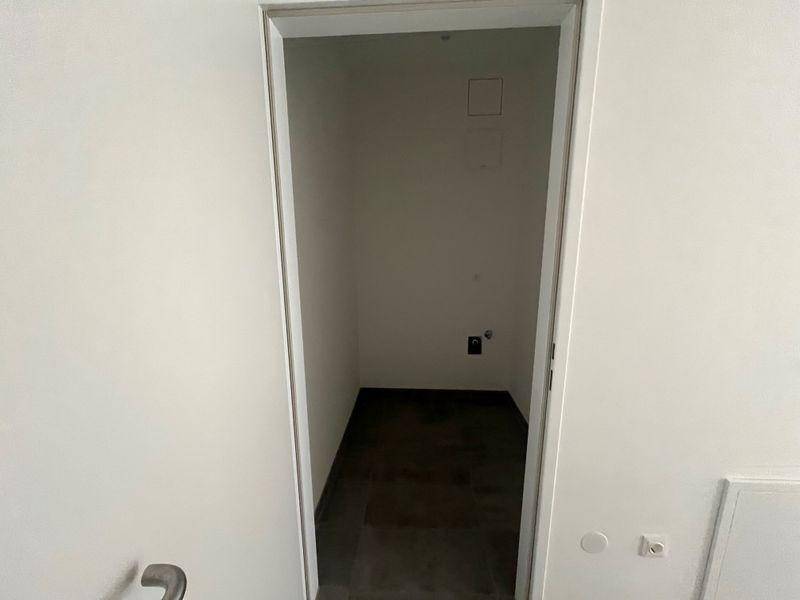 Kleiner, leerer Abstellraum mit dunklem Fliesenboden, ideal für zusätzlichen Stauraum.