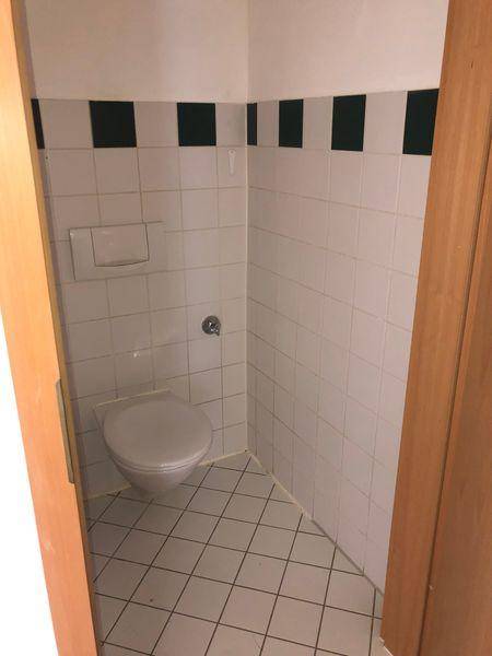 Kleines WC mit weißen Fliesen und dunklen Akzenten, funktional und sauber.