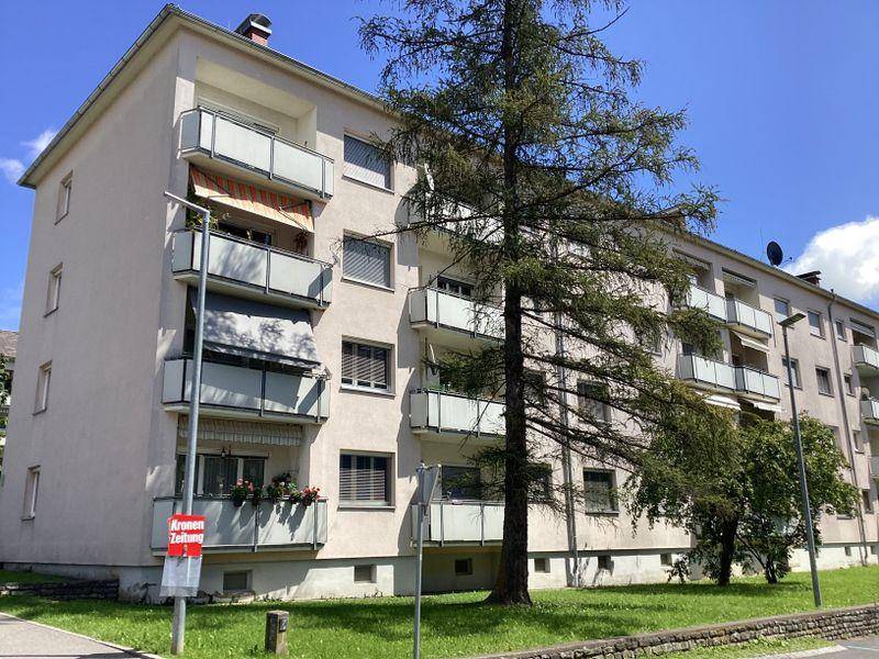 Wohngebäude mit mehreren Balkonen und gepflegter Grünfläche an einem sonnigen Tag.