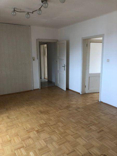 Geräumiges Zimmer mit Parkettboden und mehreren Türen, bereit zur individuellen Gestaltung.