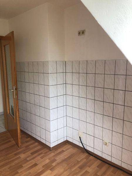Küche mit Laminatboden und weißen Wandfliesen, bereit für die Installation einer Einbauküche.