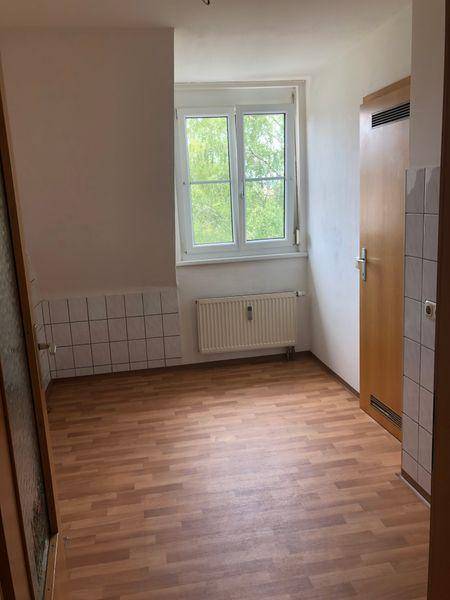 Helle Küche mit Laminatboden, teilgefliesten Wänden und Blick ins Grüne.