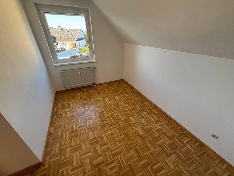Gemütliches Zimmer mit Parkettboden und Dachschräge, ideal als Kinder- oder Gästezimmer.