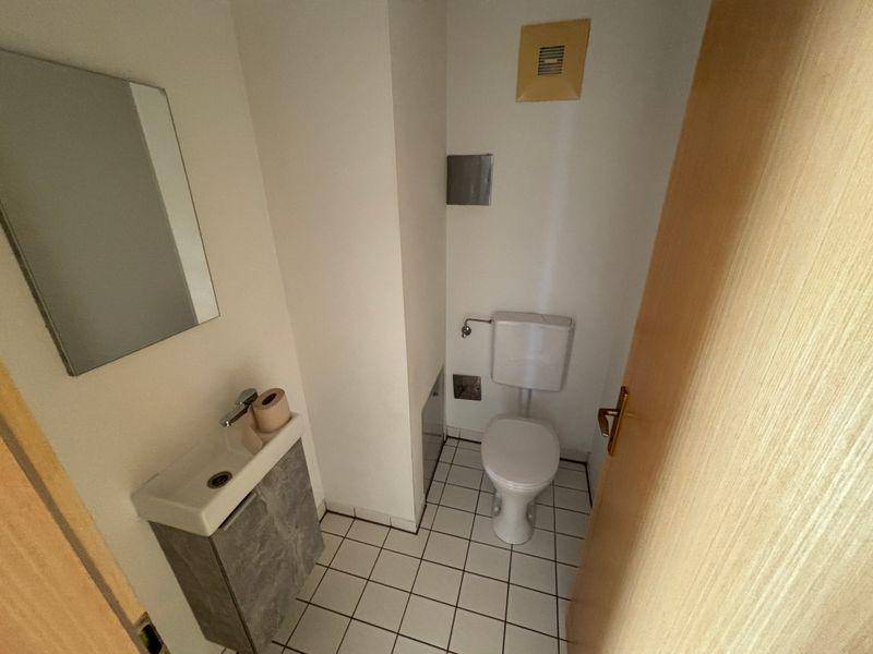 Kleines Gäste-WC mit Fliesenboden, Waschbecken und Toilette, funktional eingerichtet.