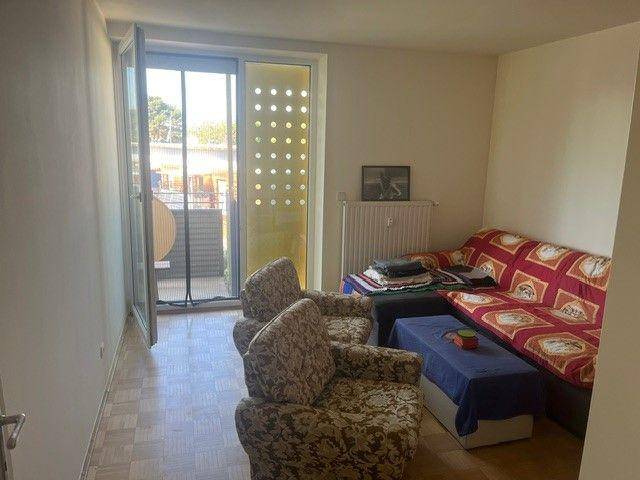 Gemütliches Wohnzimmer mit Sofa, Sesseln und direktem Balkonzugang für viel Licht.