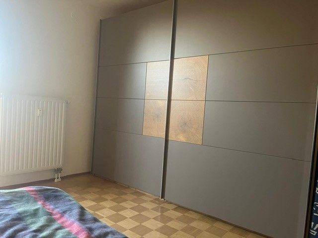 Schlafzimmer mit großem, modernem Schiebetürenschrank und Laminatboden.