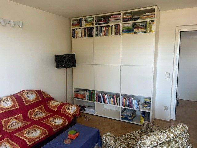 Wohnzimmer mit großem, weißem Bücherregal, Sofa und Stehlampe für gemütliche Abende.
