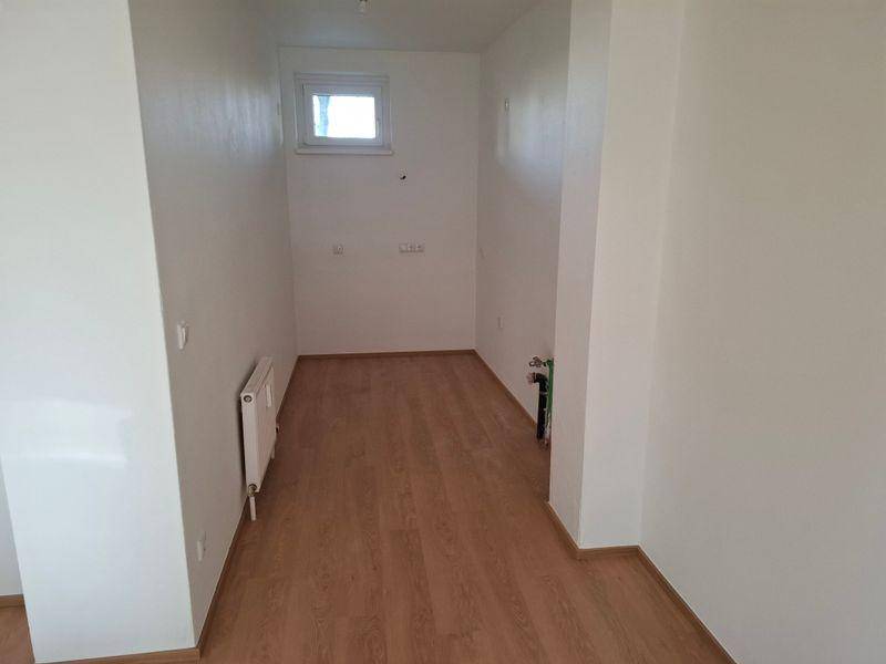 Kleiner Abstellraum mit Laminatboden, kleinem Fenster und Heizkörper, ideal für Lagerzwecke.