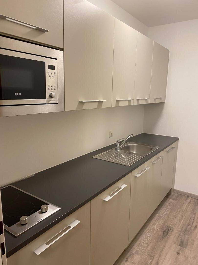 Moderne Küchenzeile mit Mikrowelle, Kochfeld und Spüle, ideal für kleine Büros oder Apartments.