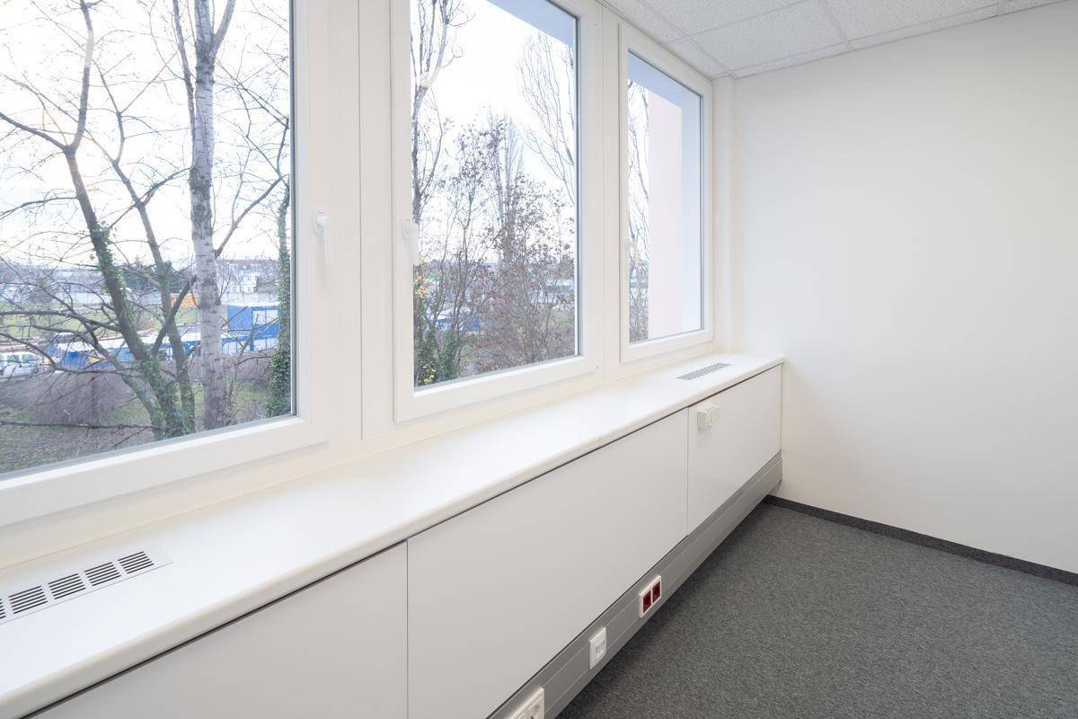 Detailansicht der großen Fensterfront in einem Büro mit Heizkörperverkleidung und Blick ins Grüne.