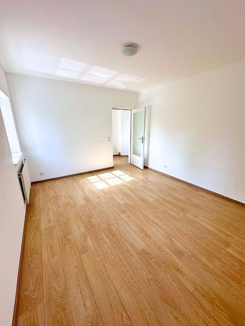 Freundliches Zimmer mit Laminatboden und viel Tageslicht, ideal als Schlaf- oder Arbeitszimmer.