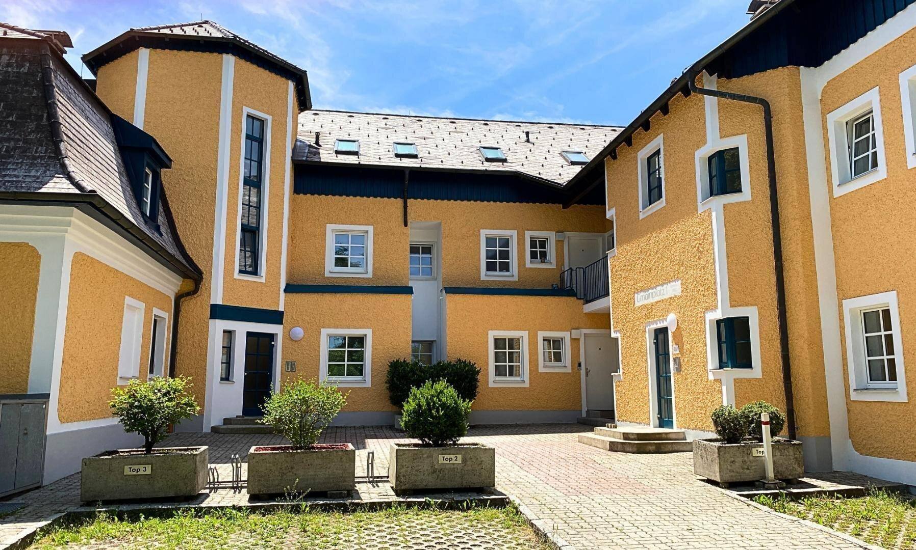 Attraktives Gebäudeensemble in Gelb mit traditioneller Architektur und Innenhof.