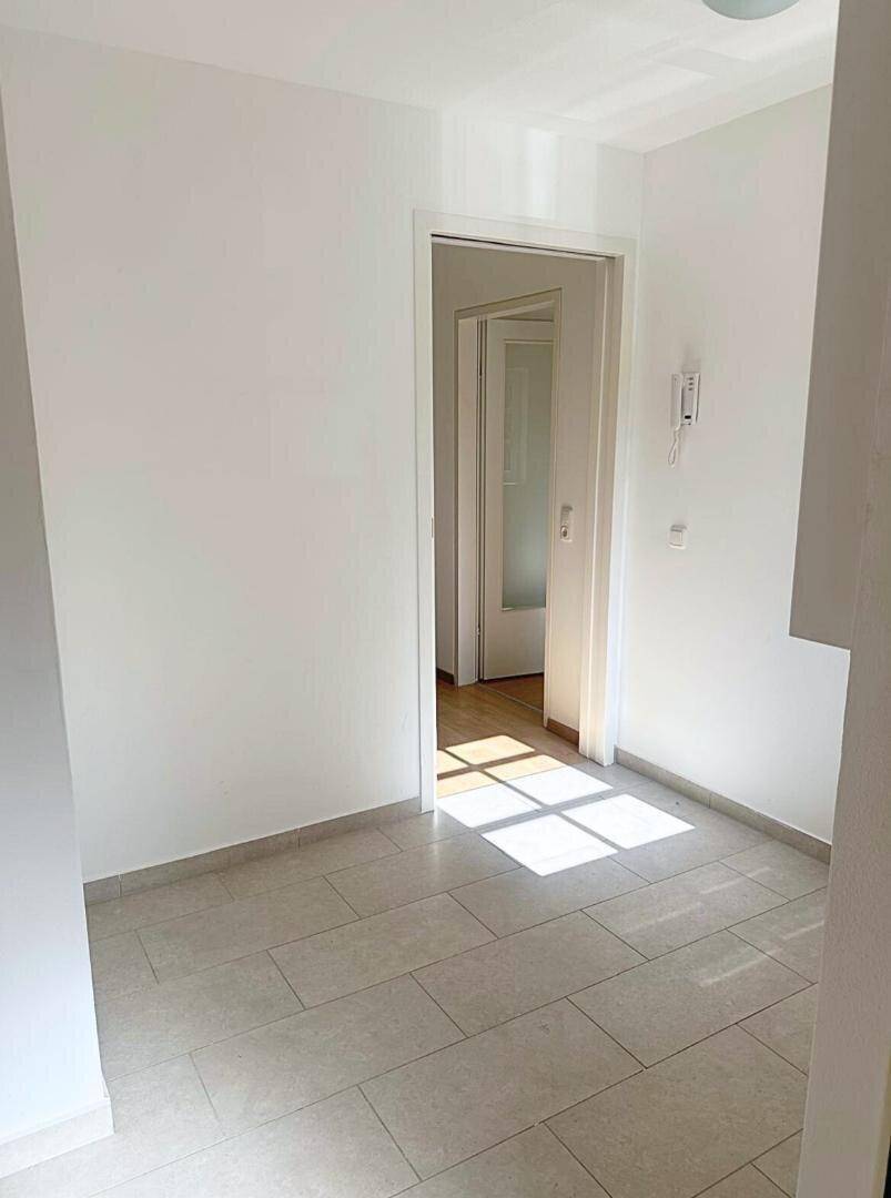Heller Eingangsbereich mit Fliesenboden und viel natürlichem Licht, der zu weiteren Räumen führt.