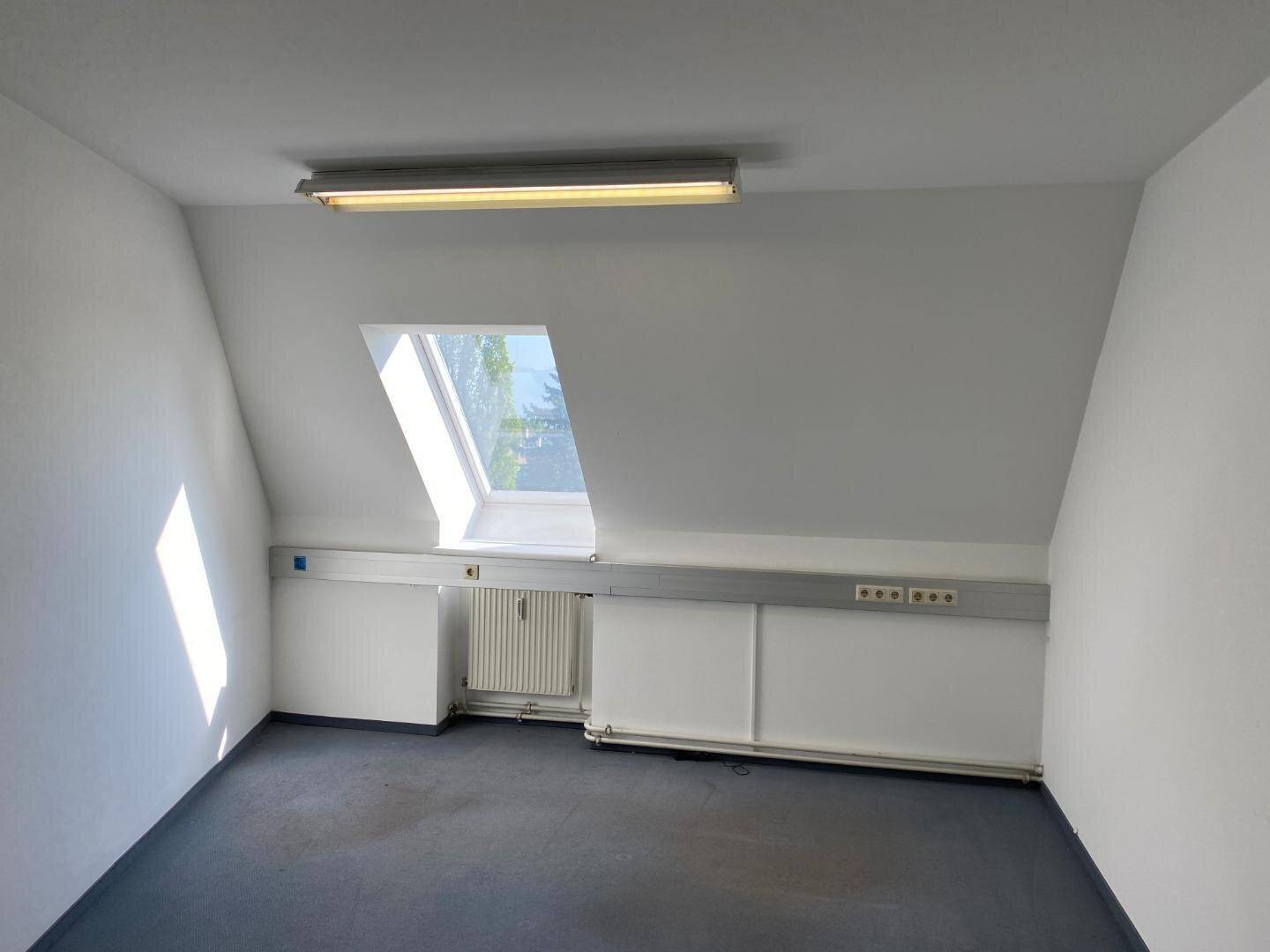 Heller Büroraum im Dachgeschoss mit schräger Decke, einem Dachfenster und Heizkörper.