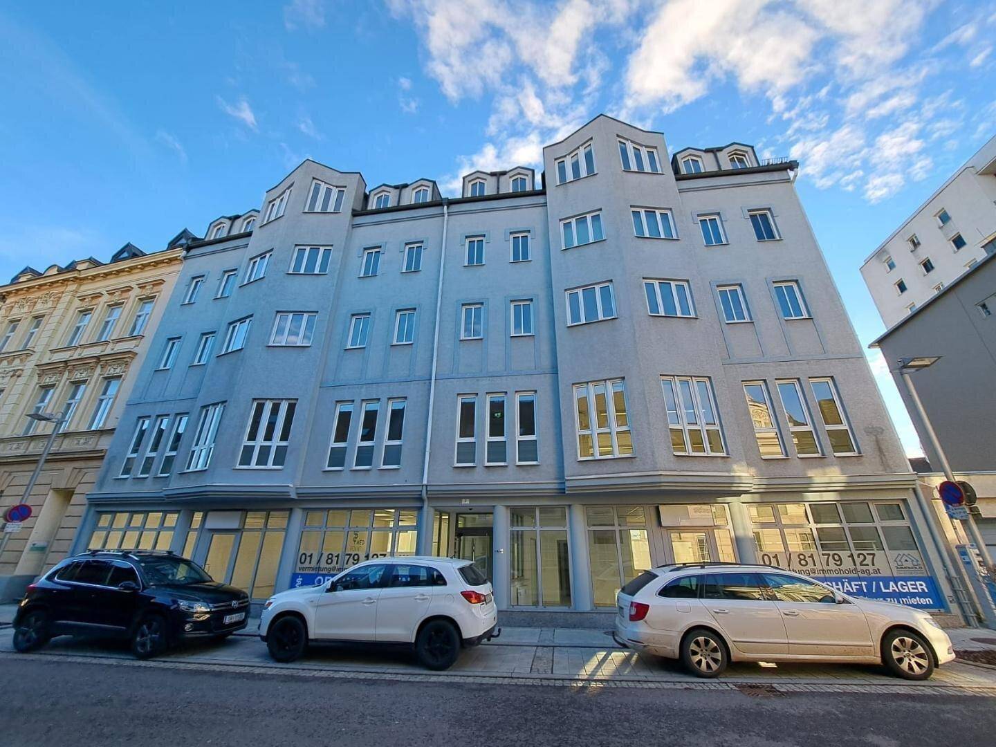 Modernes Mehrfamilienhaus mit mehreren Etagen und großen Fenstern, gelegen an einer Stadtstraße.