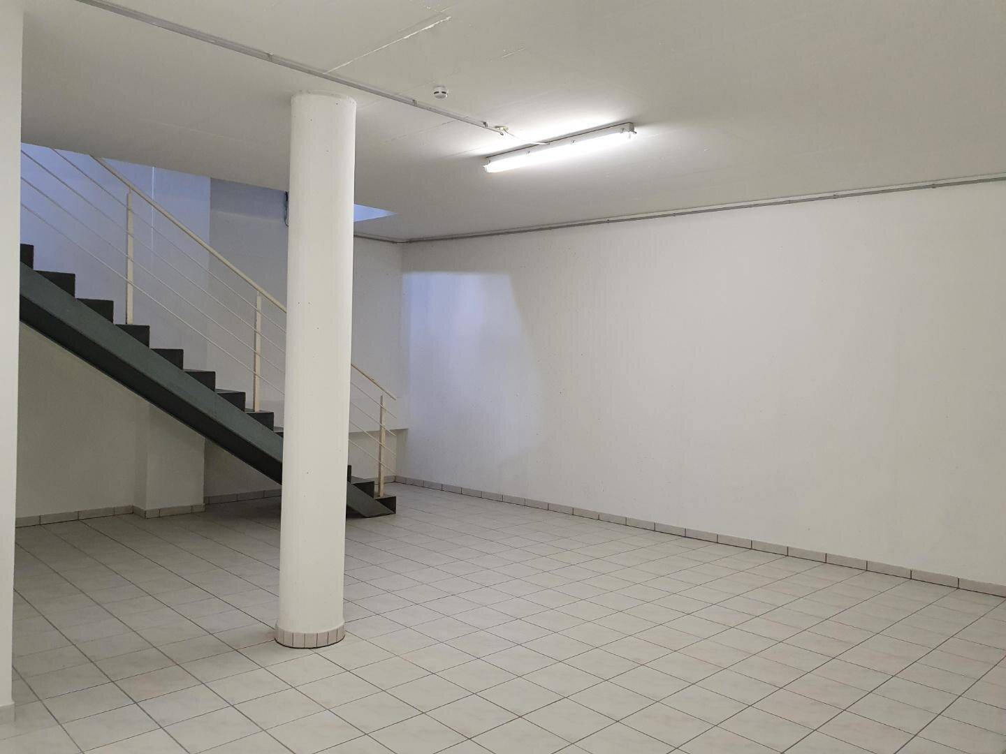 Geräumiger, heller Innenraum mit Treppe, Säule und Fliesenboden, ideal für gewerbliche Nutzung.