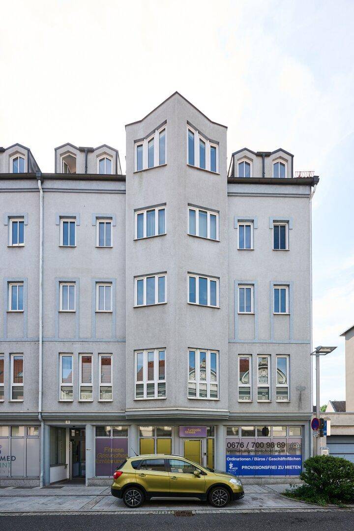 Mehrstöckiges Gebäude mit Geschäftsflächen im Erdgeschoss und einer modernen Fassade.