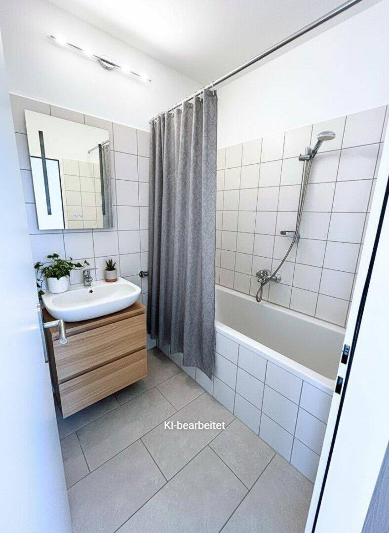 Modernes Badezimmer mit Badewanne, Duschvorhang und hellen Fliesen.