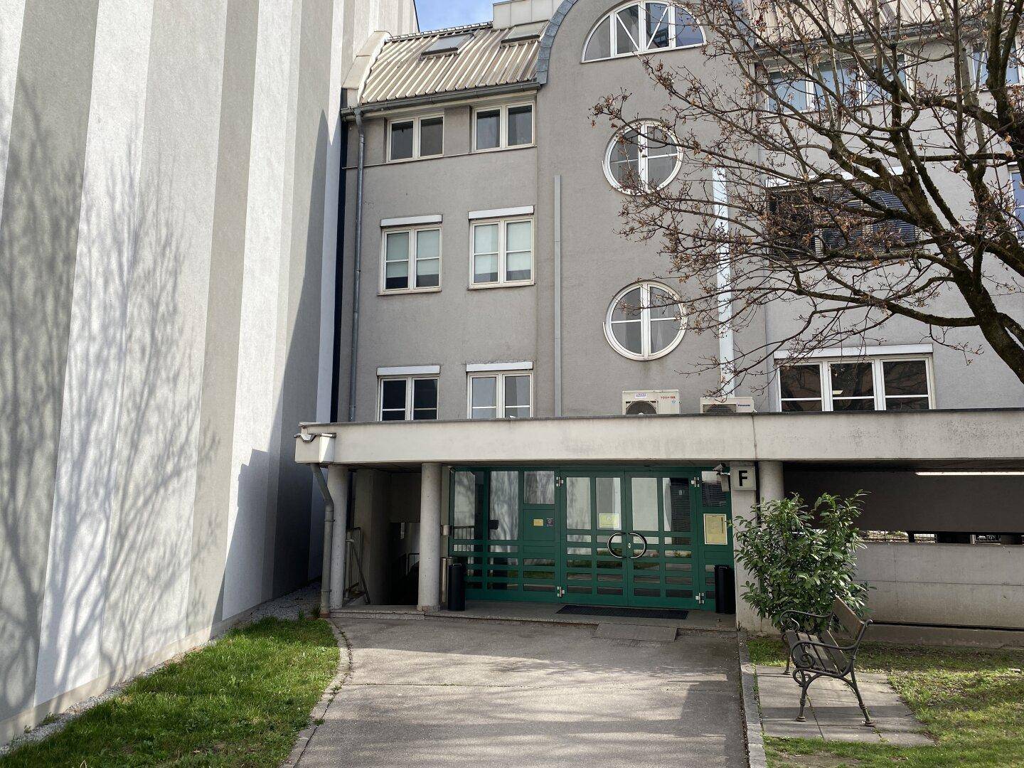 Eingangsbereich eines Gebäudes mit grüner Tür und umliegender Architektur.