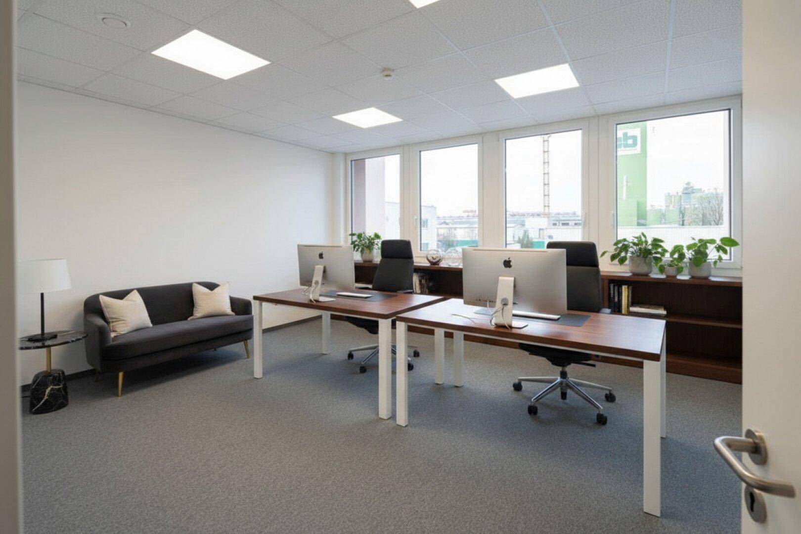 Modernes Büro mit zwei Arbeitsplätzen, bequemer Couch und Blick auf die Umgebung.