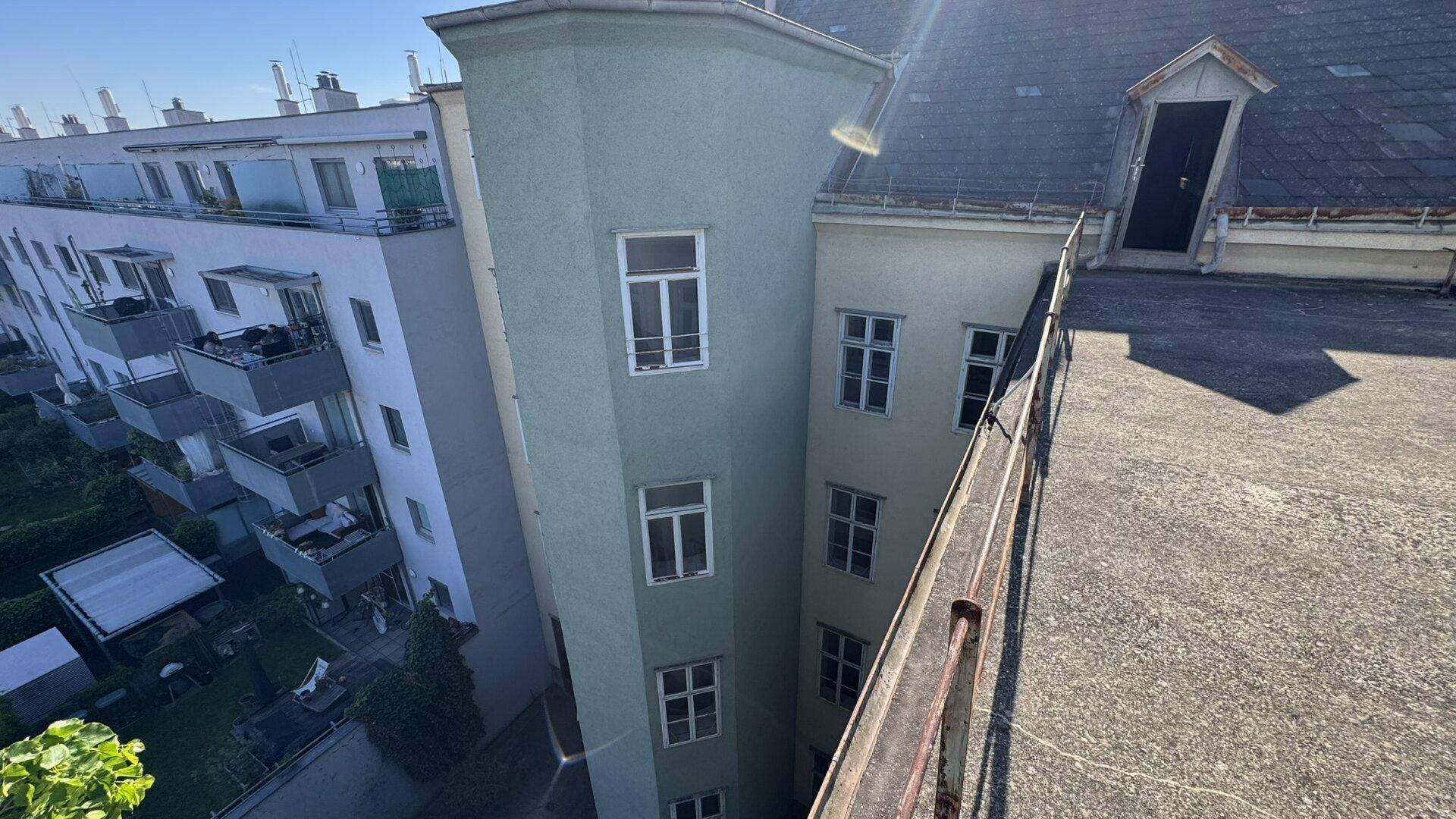 Blick von der Dachterrasse auf den Innenhof und angrenzende Gebäude mit Mansarddach.