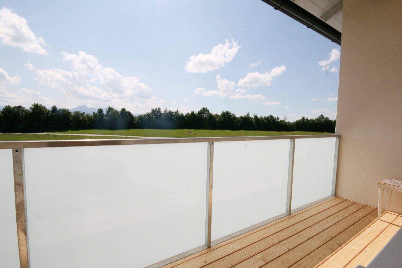 Heller Balkon mit Holzboden und Milchglasbrüstung bietet weiten Blick ins Grüne.