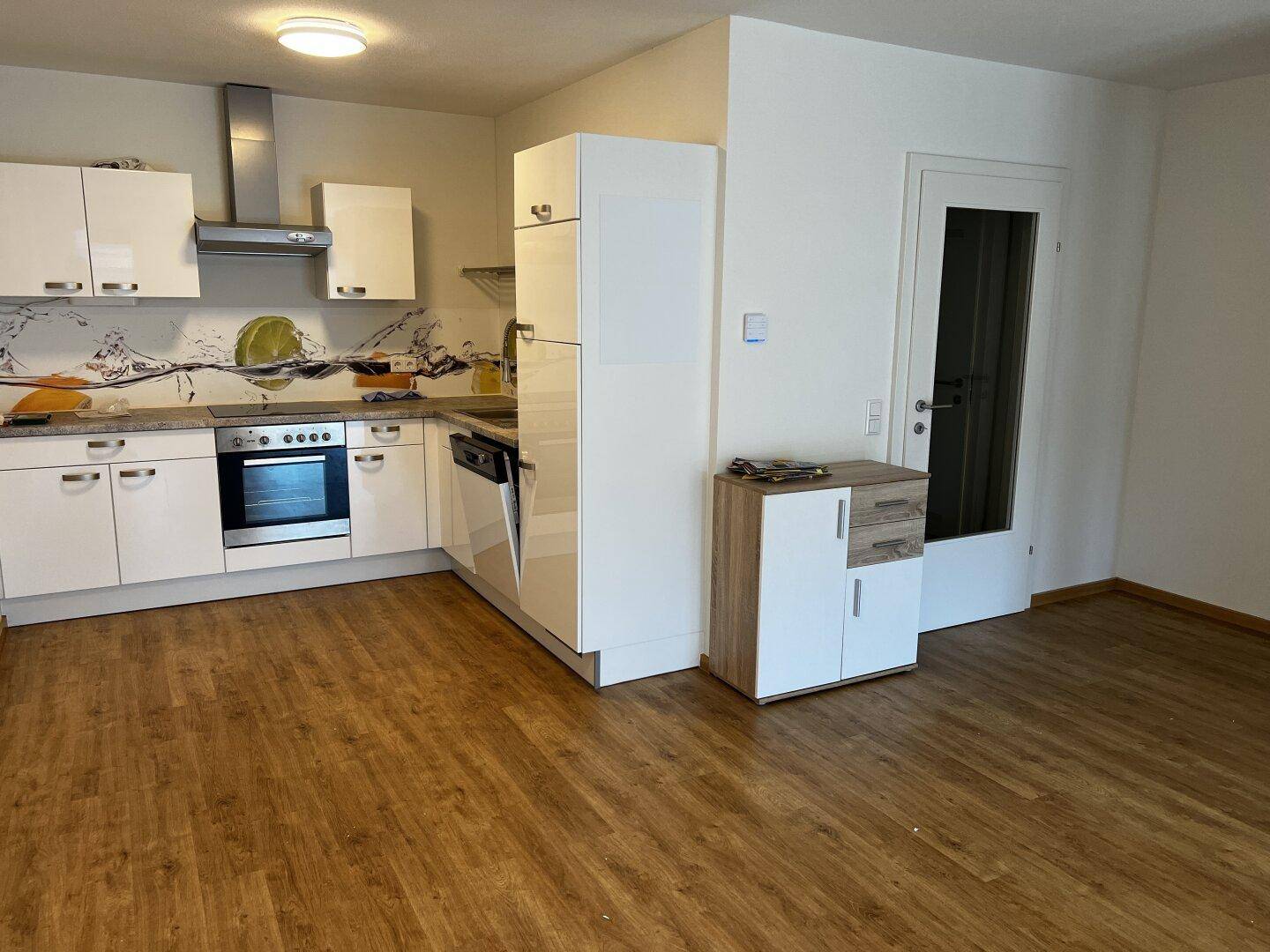 Moderne Einbauküche mit weißen Hochglanzfronten, integrierten Geräten und heller Arbeitsplatte.