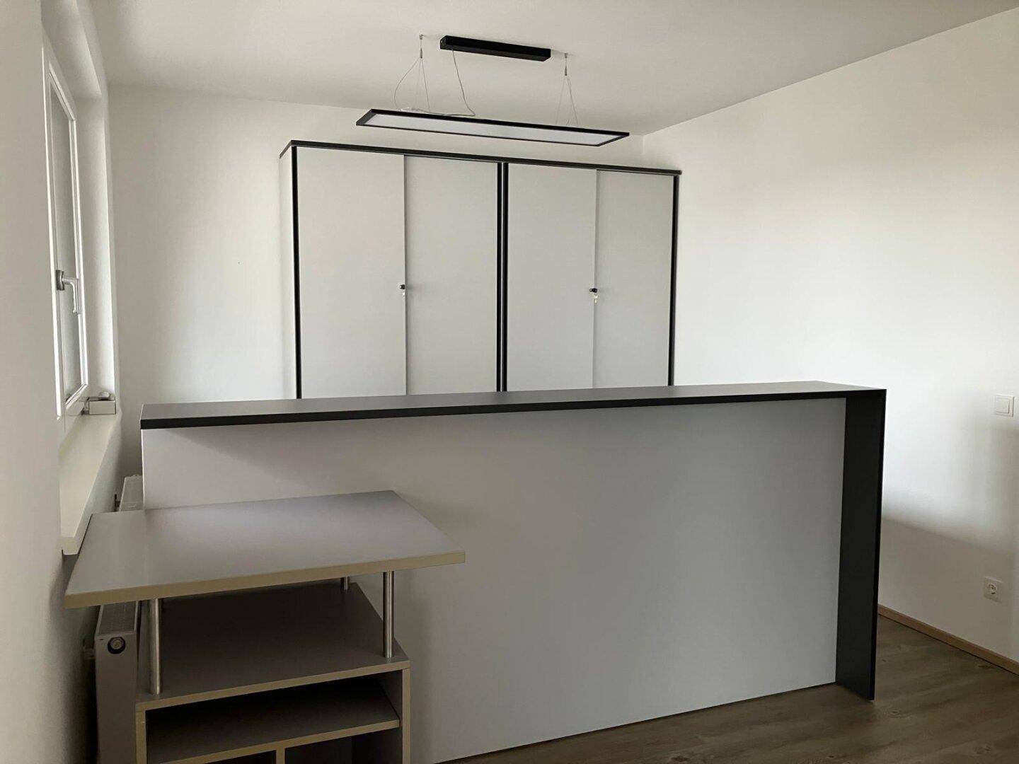 Heller Büroraum mit moderner Theke, Einbauschränken und Deckenleuchten.