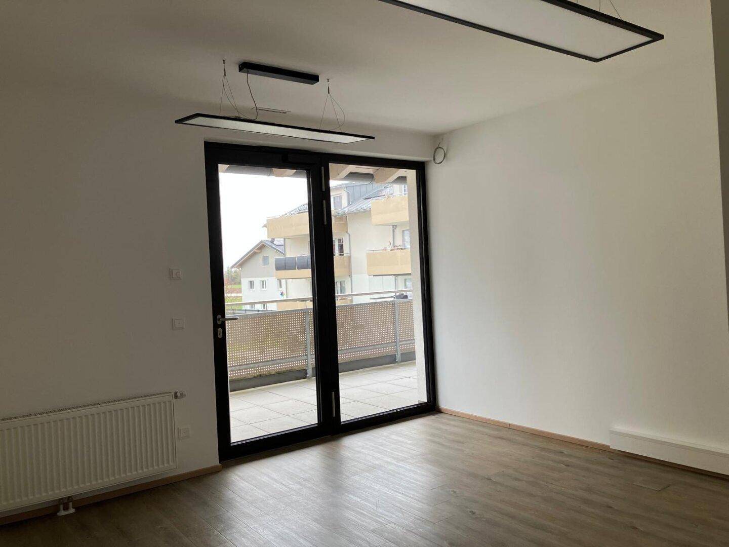 Heller Raum mit Zugang zu einem Balkon und Blick auf umliegende Gebäude.