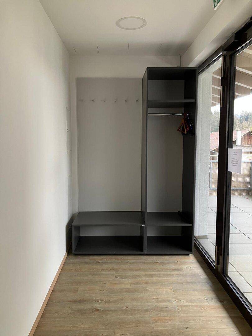 Heller Eingangsbereich mit Garderobe, Ablageflächen und Zugang zum Balkon.