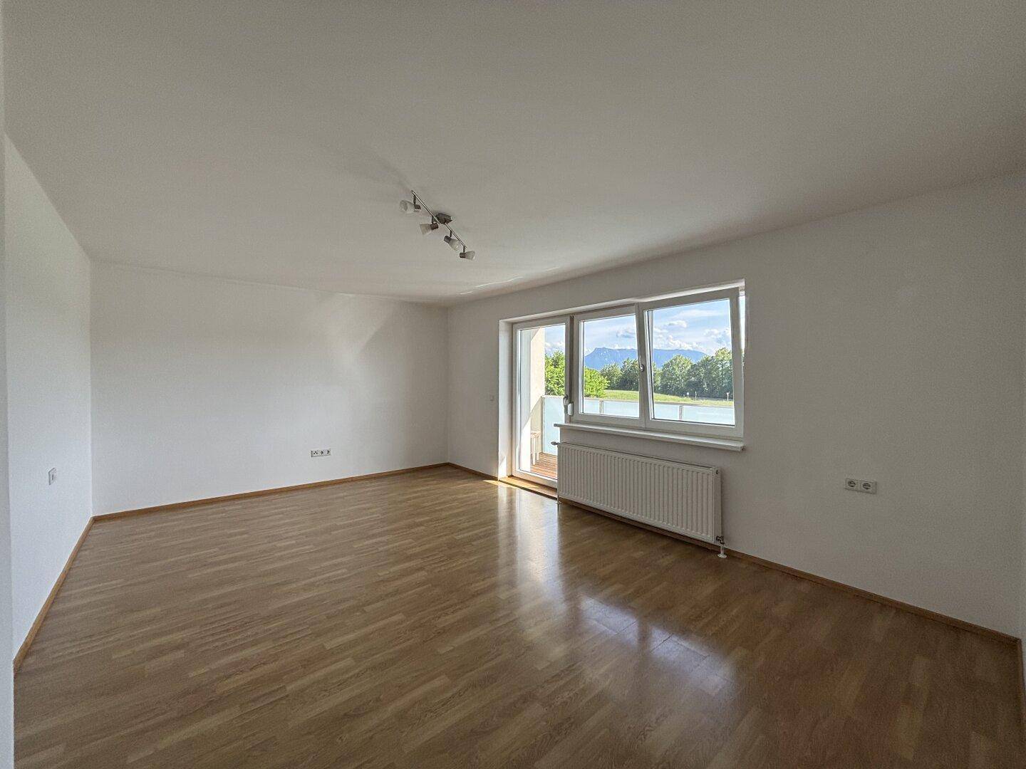 Lichtdurchfluteter Raum mit Holzparkett und weitem Ausblick auf die umliegende Berglandschaft.